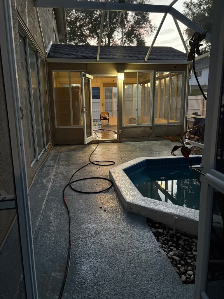 Wet concrete patio and pool deck inside a screened Florida lanai after cleaning